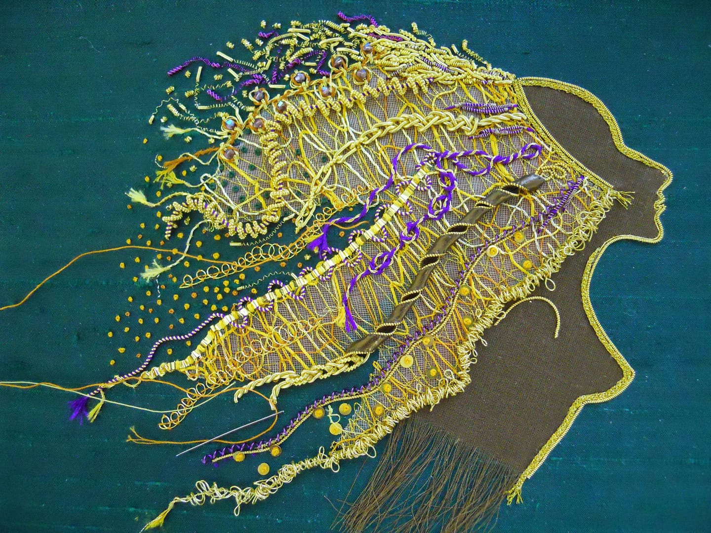 French knots and gold spangles are added to Lion Woman's mane